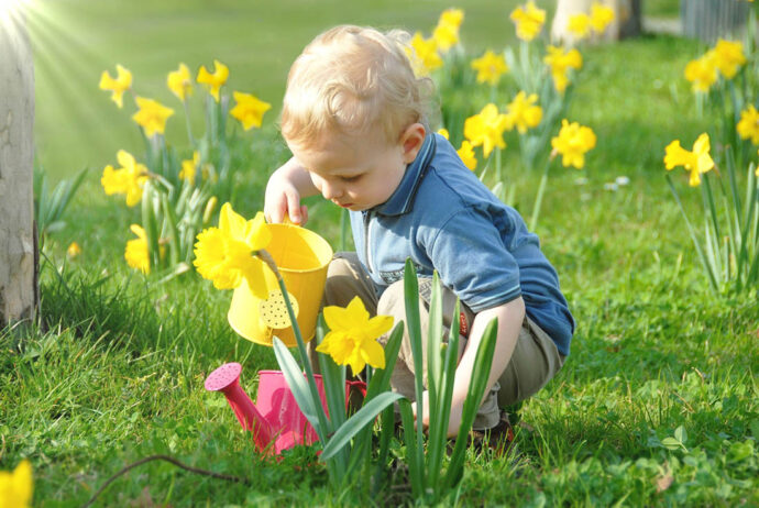 Kind gießt Blumen bei schönem Wetter