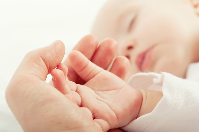 schlafendes Baby hand in hand mit Mutter