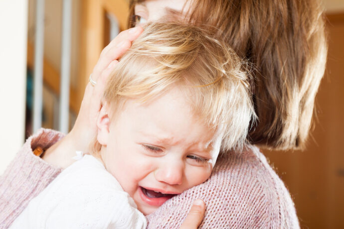 Mutter hält weinendes Kleinkind im Arm