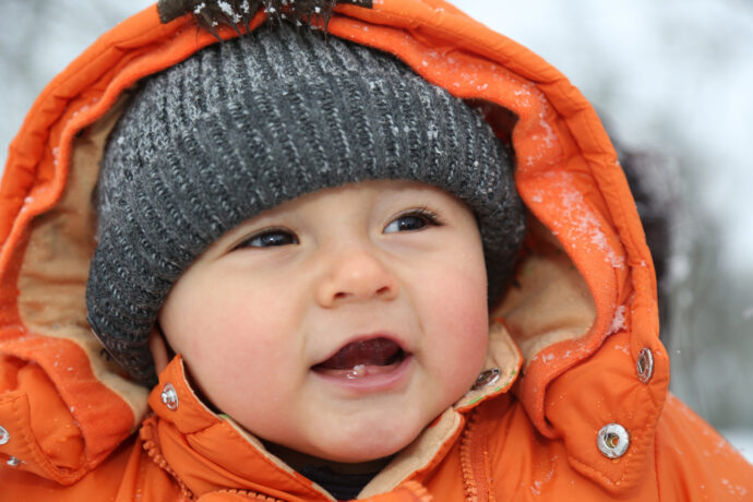 Portrait lachendes Baby im Schnee im Winter