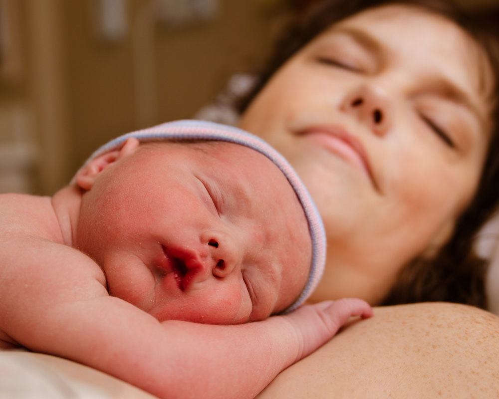 Bonding: Neugeborenes Baby kuschelt mit seiner Mama