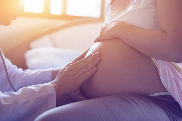 arzt betastet bauch einer schwangeren vor eipolloesung zur geburtseinleitung