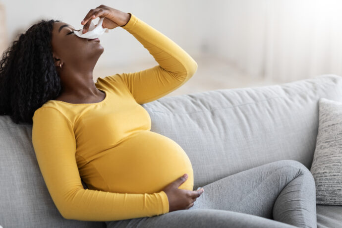 schwangere frau sitzt mit nasenbluten in der schwangerschaft kopf in den nacken gelegt