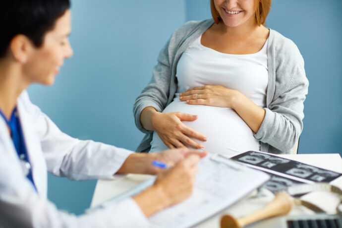 glückliche schwangere frau bei vorsorge untersuchungen in der schwangerschaft mit aerztin