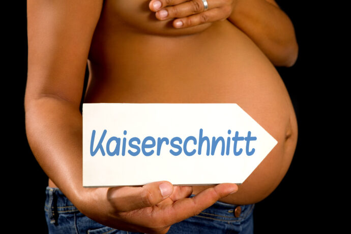 nahaufnahme babybauch schwangere mit schild vorbereitung auf kaiserschnitt