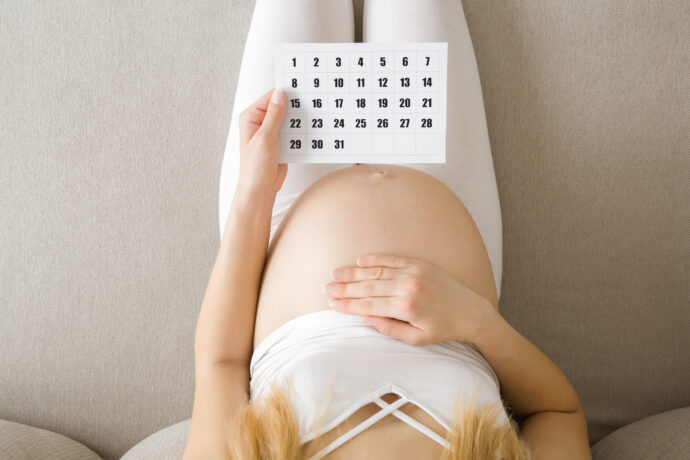 Kaiserschnitt berechnen, schwangere Frau hält Kalender für Geburtstermine