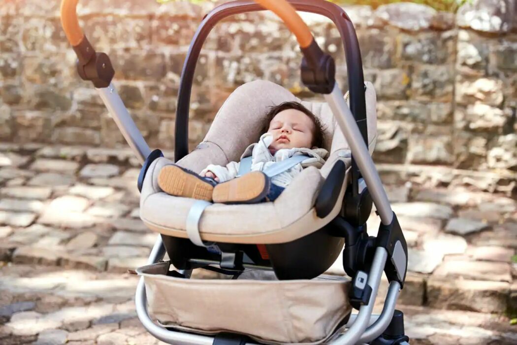 baby schlaeft in maxi-cosi babyschale auf einem kinderwagen gestell