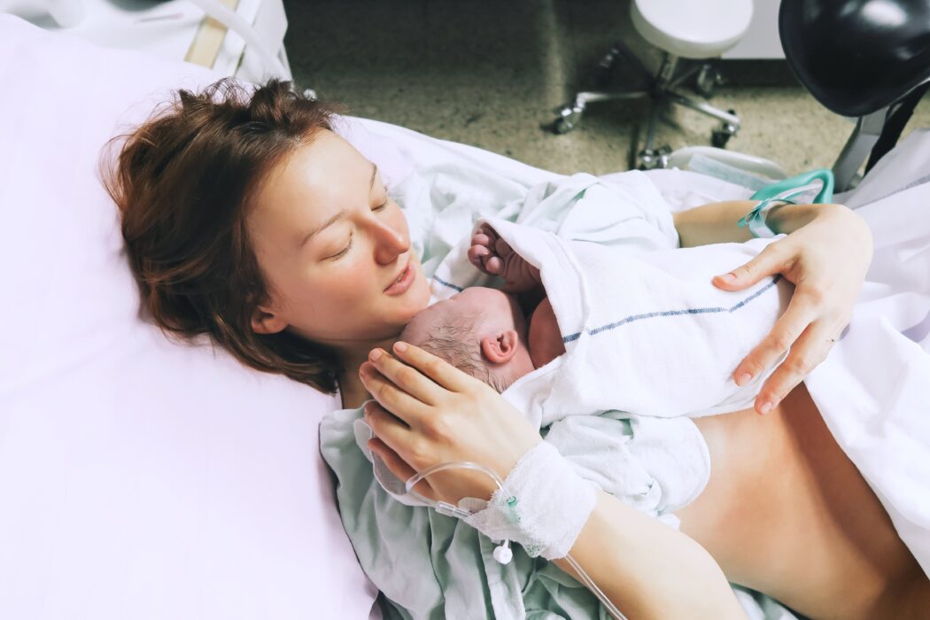 4 phasen der geburt frischgebackene mutter hält neugeborenes baby im kreißsaal