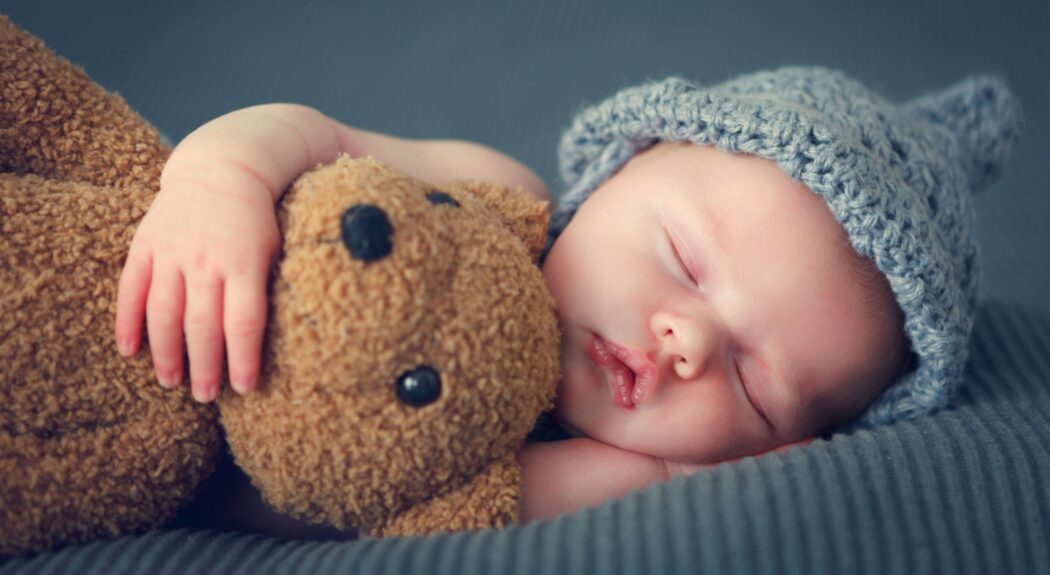 neugeborenes baby junge mit strickmütze und teddybär glückwünsche