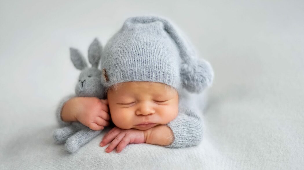 glückwünsche zur geburt neugeborenes mit mütze und stoffhase schläft