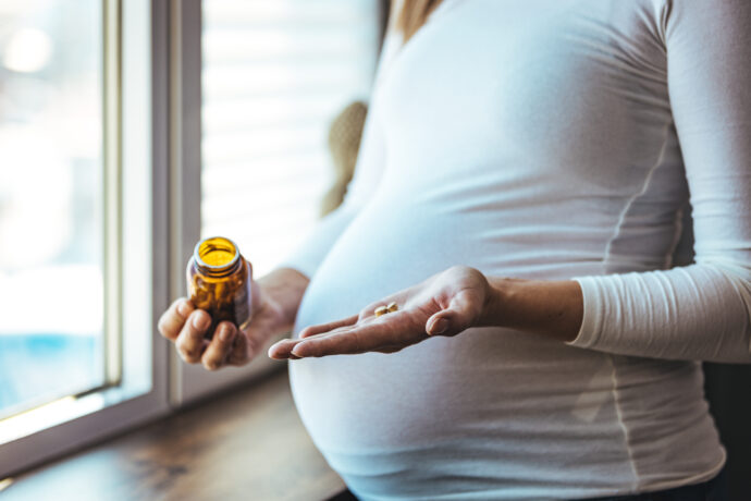 Schwangere Frau nimmt Tablette mit Nahrungsergänzung, Schwangerschaftsvitamine Test Ökotest 2023, Folsäure Tabletten Testsieger