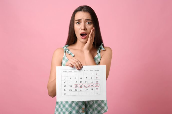 unregelmaessiger zyklus besorgte frau hält kalender mit markierten tagen für blutung